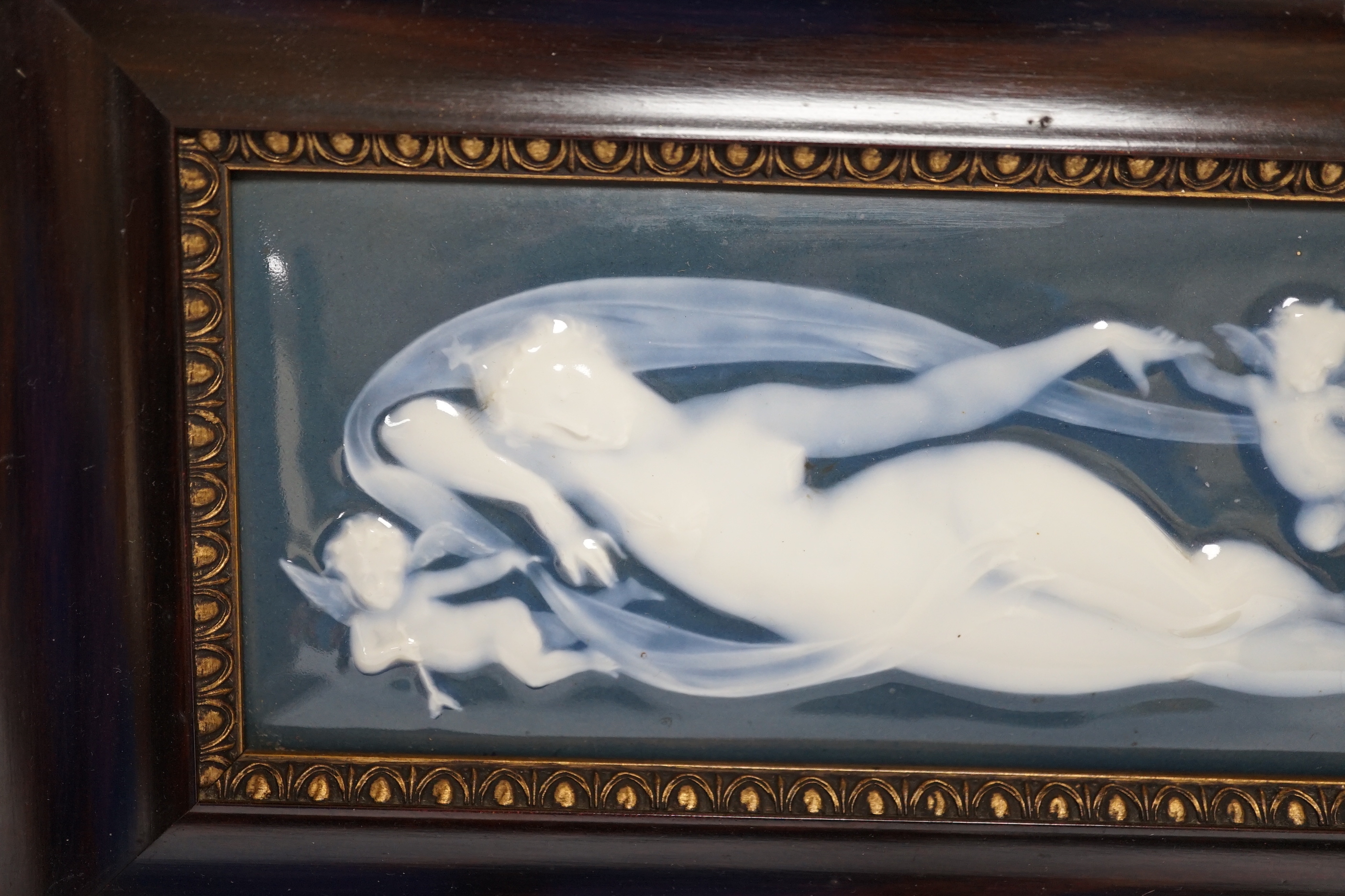 A framed Limoges pate sur pate plaque, of a reclining nude with cherubs, 31cm x 19.5cm